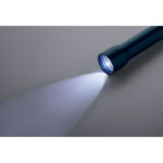 Lampe de poche allumée sur surface grise