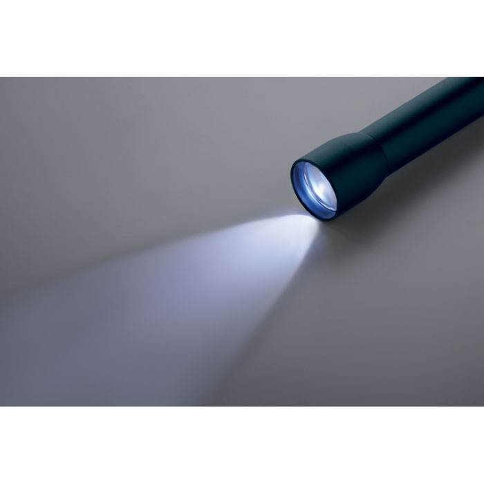 Lampe de poche allumée sur surface grise