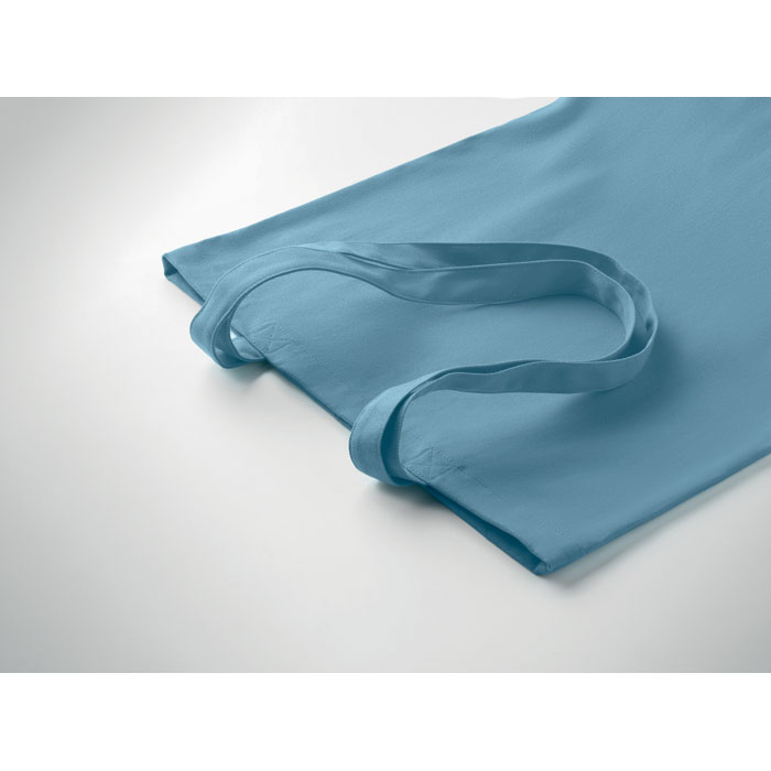 Sac en tissu bleu posé sur surface blanche