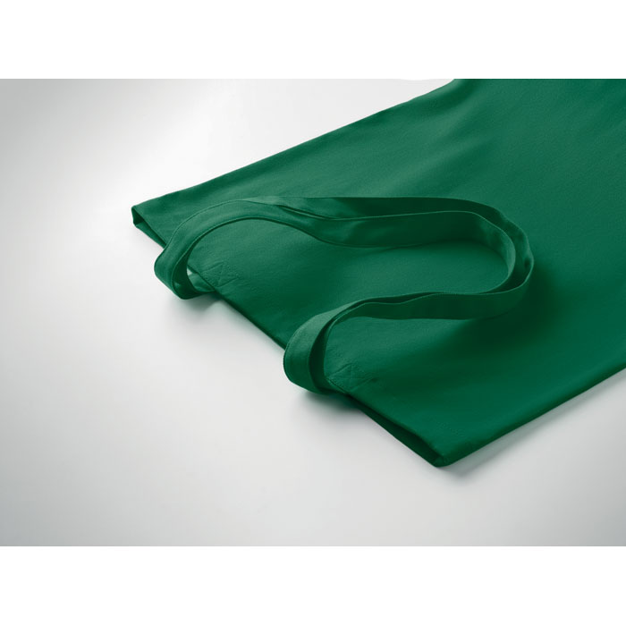 Sac en tissu vert posé sur surface claire