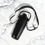 Gourde noire avec sangle sur fond marbré