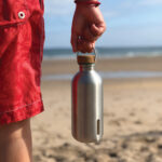 Personne tenant une gourde en métal sur la plage