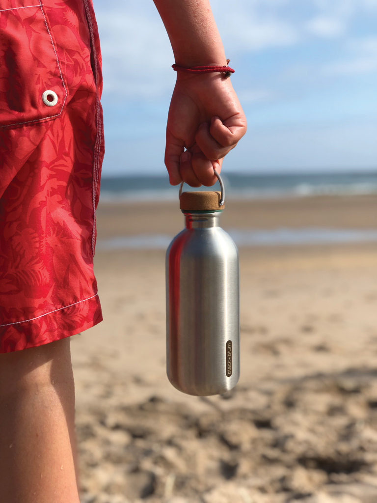 Personne tenant une gourde en métal sur la plage