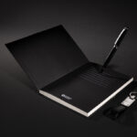 Carnet noir ouvert avec stylo et porte-clés.