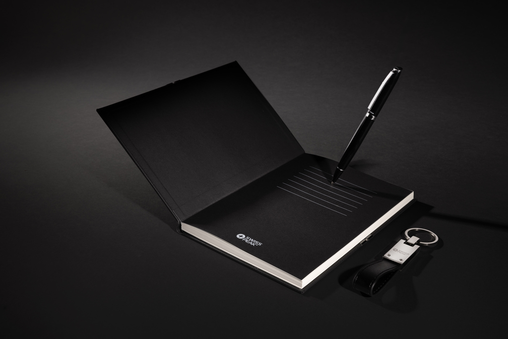 Carnet noir ouvert avec stylo et porte-clés.