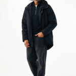 Homme portant manteau noir et pantalon ample