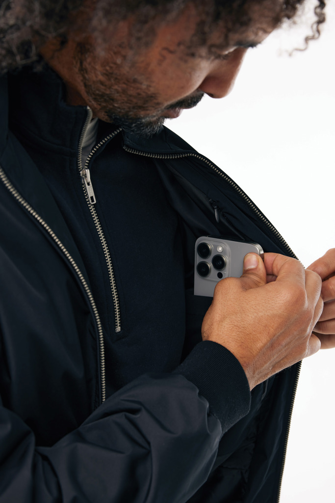 Homme range un smartphone dans sa poche intérieure
