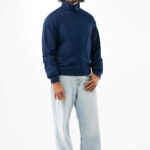 Homme portant blouson bleu et jean clair.