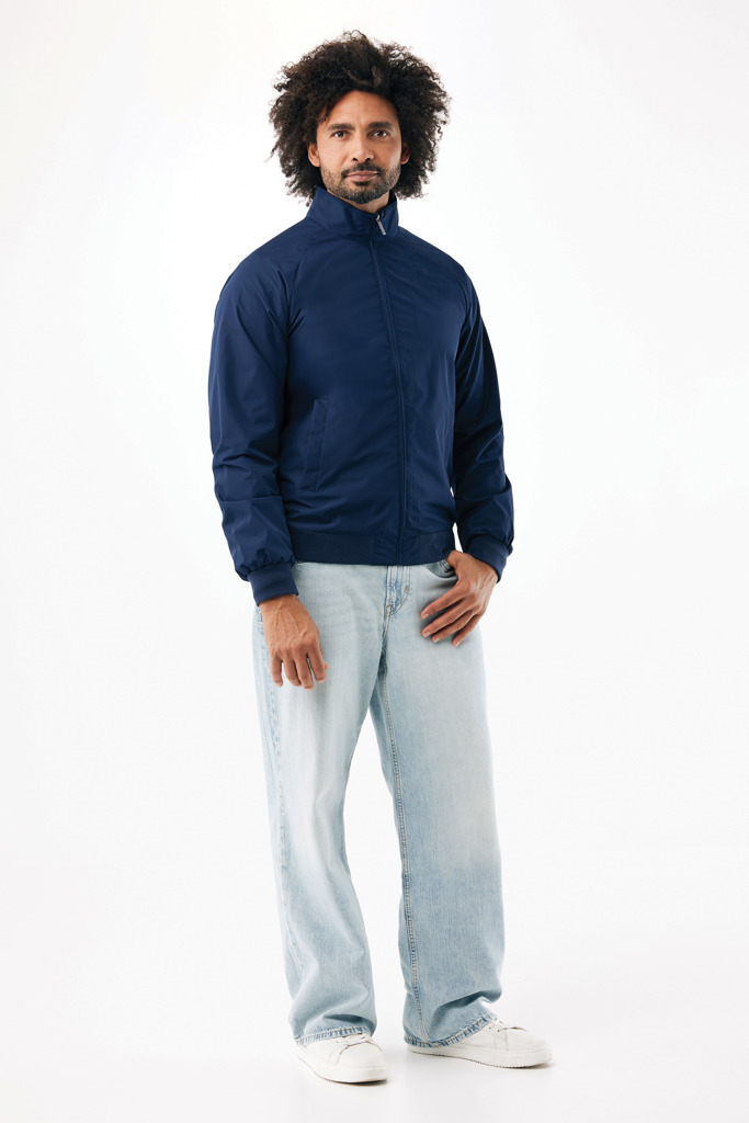 Homme portant blouson bleu et jean clair.