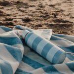 Gourde bleue sur serviette rayée à la plage