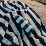 Bouteille bleue sur serviette rayée à la plage