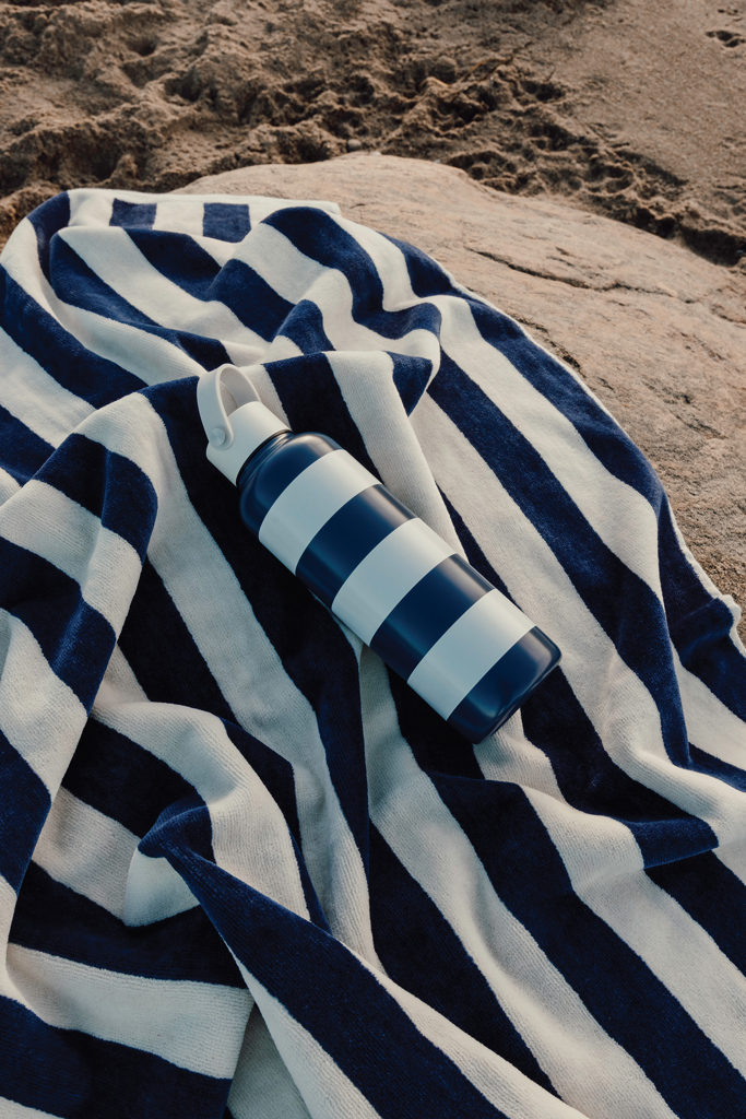 Bouteille bleue sur serviette rayée à la plage