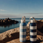 Deux bouteilles rayées sur un rocher en bord de mer