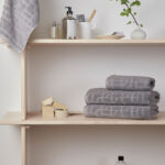 Étagères de salle de bain avec serviettes grises et accessoires.