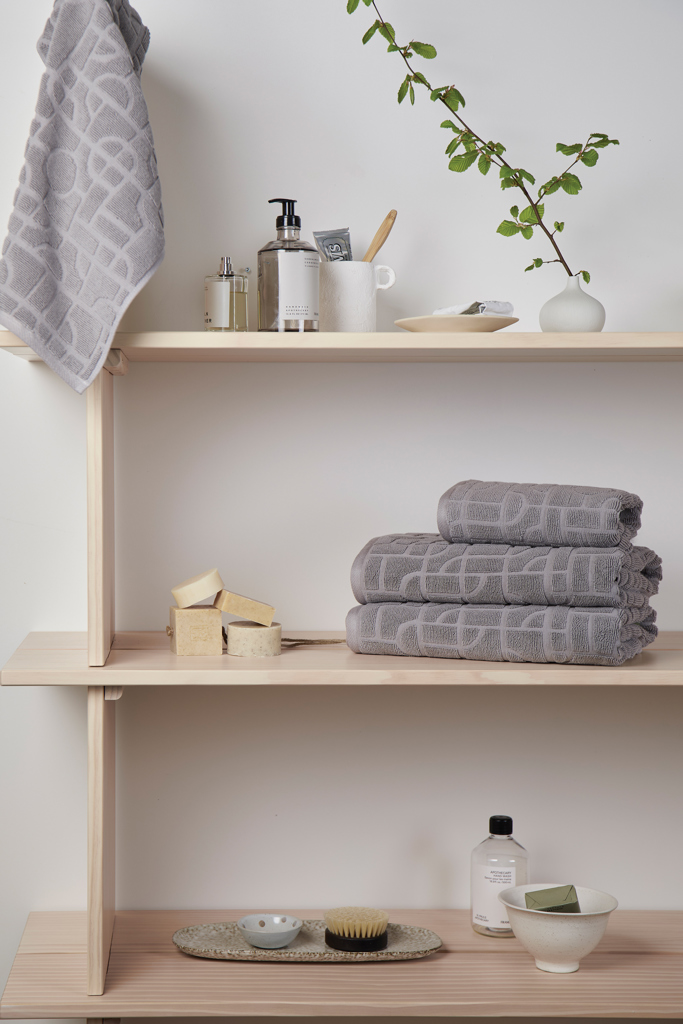 Étagères de salle de bain avec serviettes grises et accessoires.