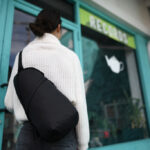Personne entrant dans un magasin turquoise avec sac noir