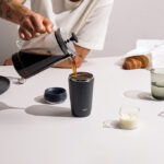 Personne versant du café dans un gobelet noir