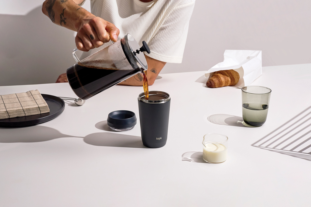 Personne versant du café dans un gobelet noir