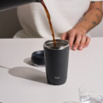 Versement de café dans un gobelet réutilisable noir