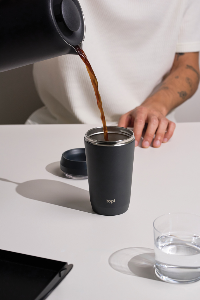 Versement de café dans un gobelet réutilisable noir