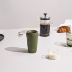 Tasse verte avec café, lait et croissant