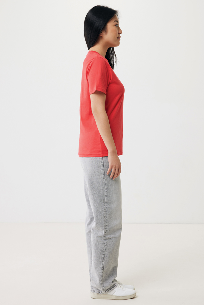 Femme de profil en t-shirt rouge et jean gris clair