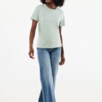 Femme souriante en t-shirt vert et jean