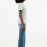 Femme de profil en t-shirt vert et jean