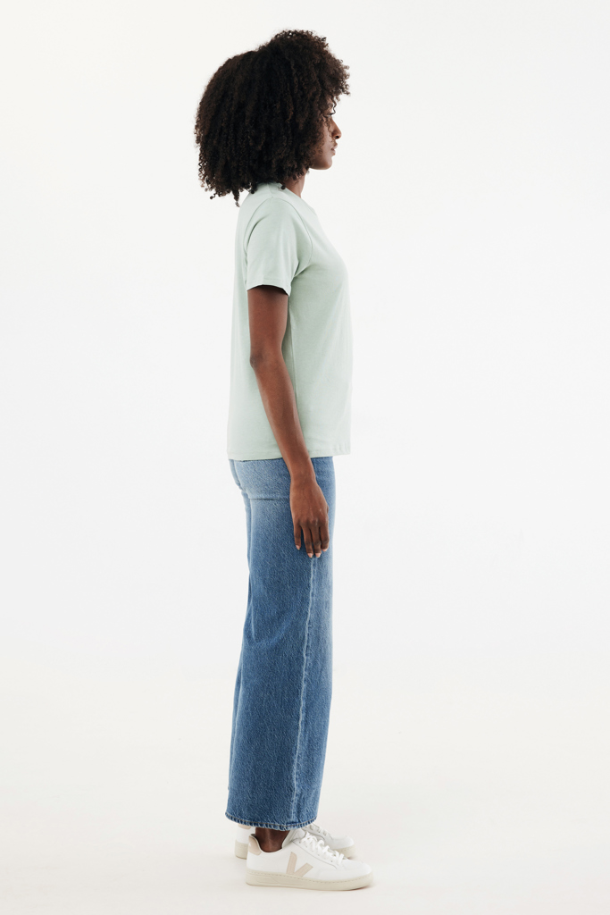 Femme de profil en t-shirt vert et jean