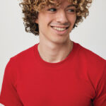 Jeune homme souriant aux cheveux bouclés, t-shirt rouge