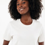 Femme souriante aux cheveux bouclés en t-shirt blanc