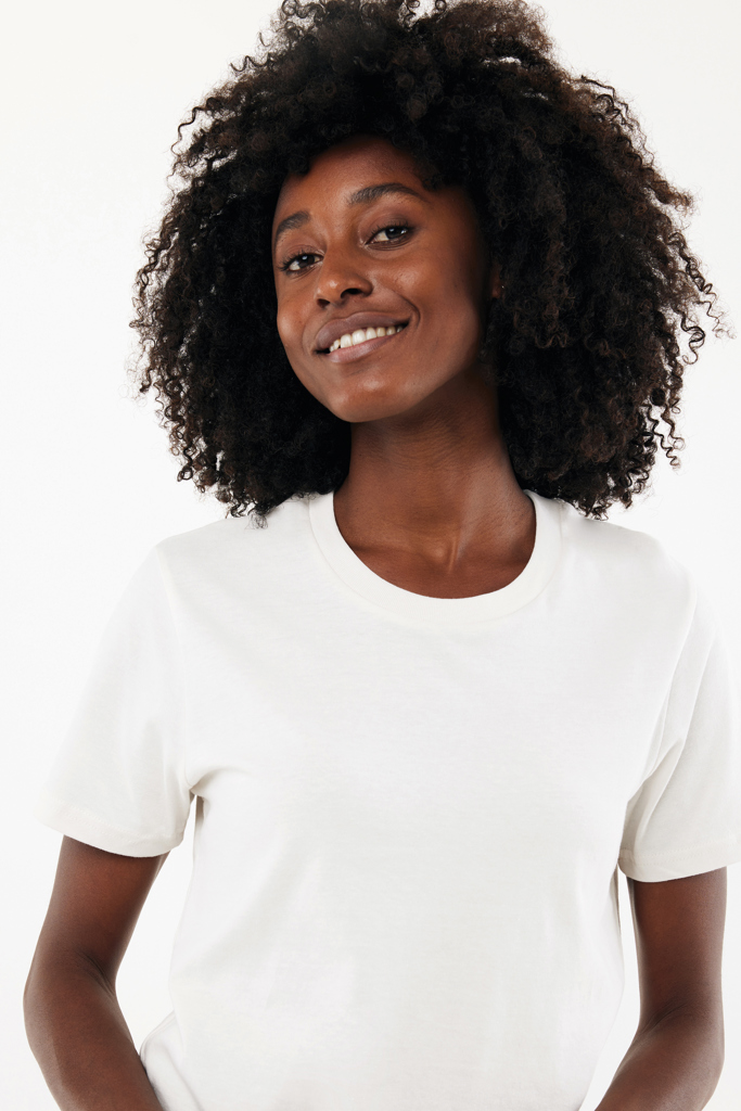 Femme souriante aux cheveux bouclés en t-shirt blanc