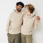 Couple souriant en sweats beiges, fond neutre