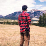 Homme en chemise rouge face aux montagnes