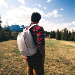 Homme avec sac à dos face aux montagnes