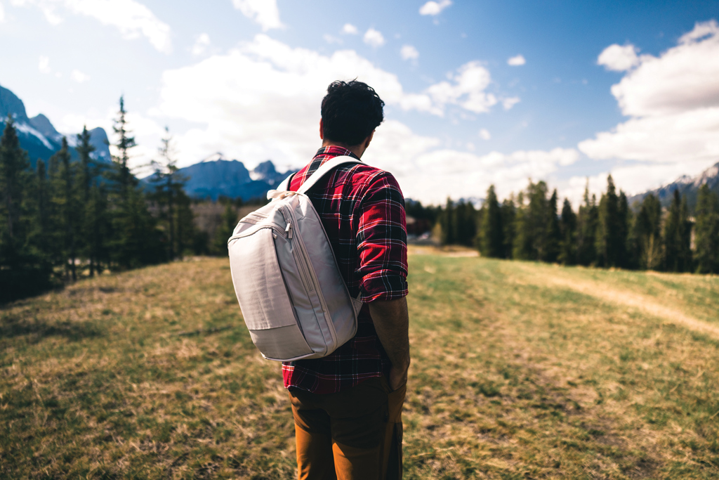 Homme avec sac à dos face aux montagnes