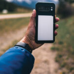 Main tenant smartphone sur sentier de montagne