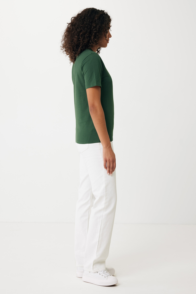 Femme de profil en t-shirt vert et pantalon blanc