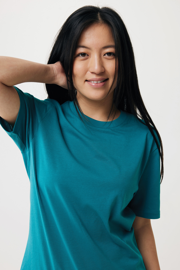 Femme souriante en t-shirt vert sur fond neutre