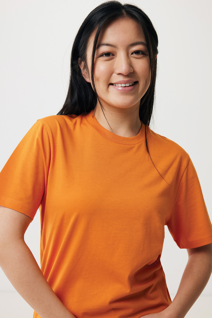 Femme souriante en t-shirt orange sur fond clair