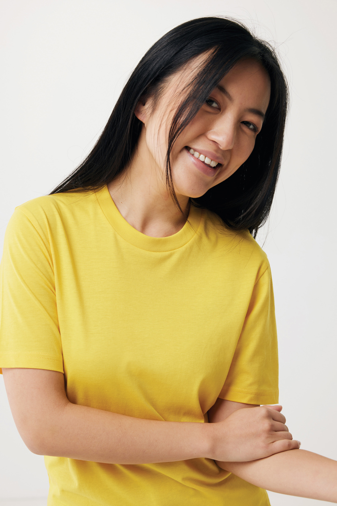 Femme souriante en t-shirt jaune sur fond clair