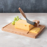 Bloc de fromage avec trancheuse et raisins verts