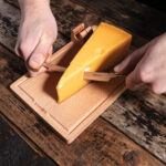 Découpe d’un morceau de fromage sur planche