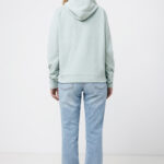 Femme de dos en hoodie vert pâle et jean clair