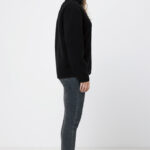 Femme en profil portant veste noire et jeans