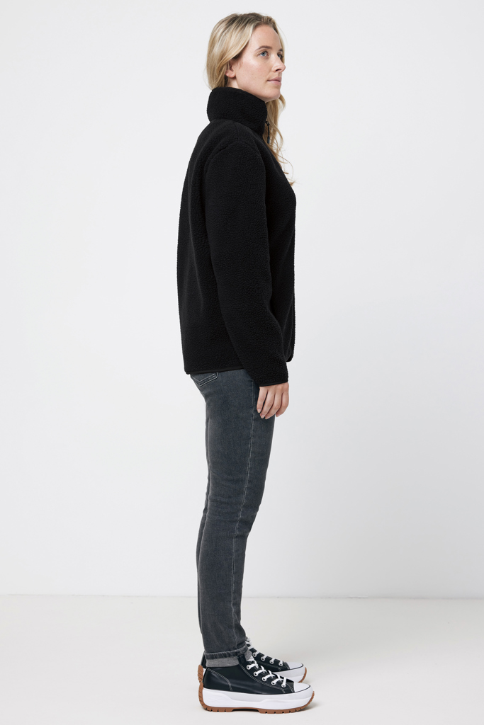 Femme en profil portant veste noire et jeans