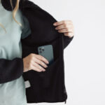 Femme range smartphone dans poche intérieure veste