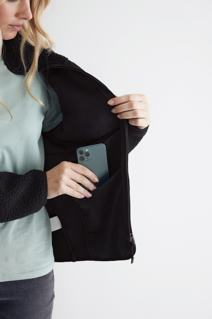 Femme range smartphone dans poche intérieure veste