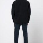 Homme de dos portant veste noire et jean