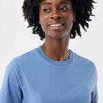 Femme souriante aux cheveux bouclés en t-shirt bleu